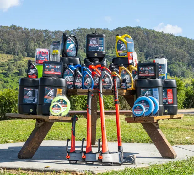 Collection of Prokut oil bottles and equipment from GA SPares on a picnic table outdoors with trees in the background.