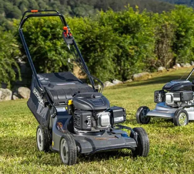 Picture of a Superswift push mower self propelled with a garden in the background and green lawn