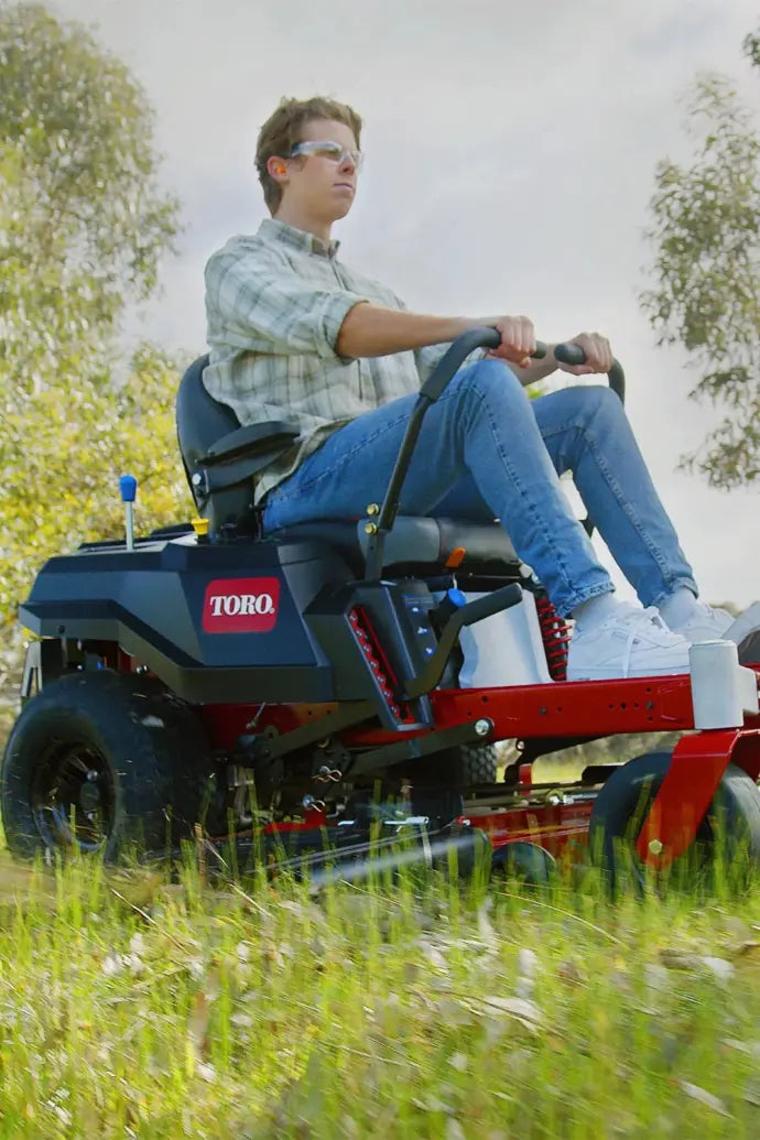 Toro Time Cutter My Ride mowing in a field with a person driving it. 
